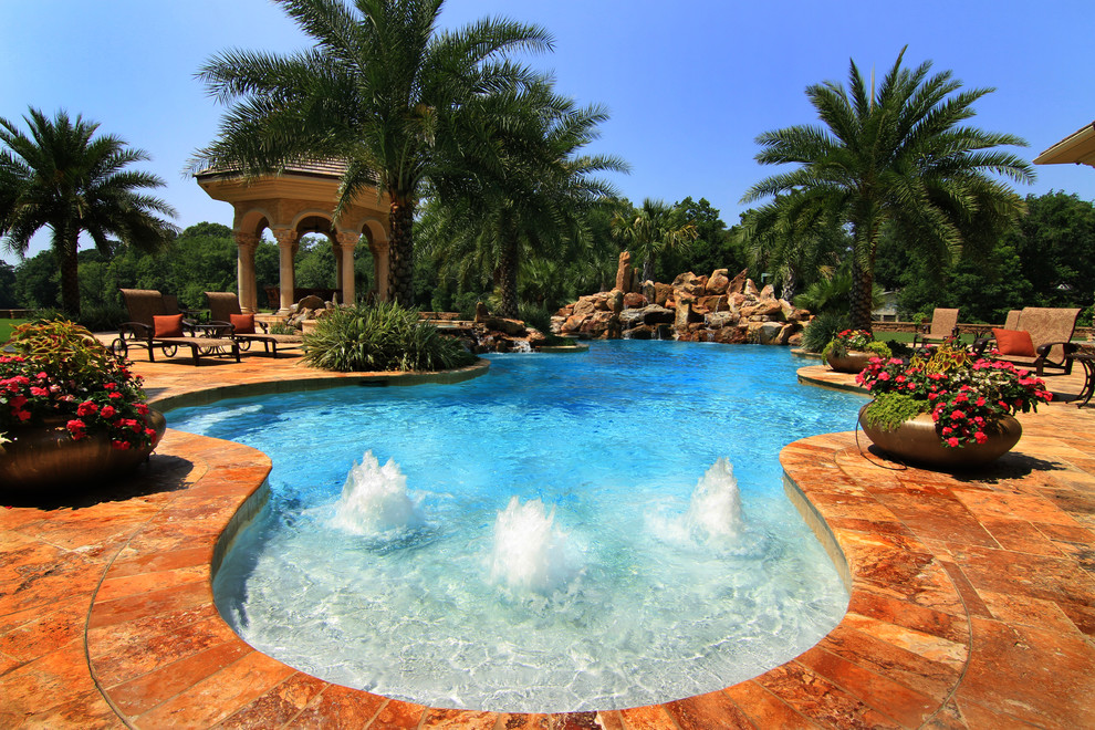 This is an example of a tropical backyard custom-shaped pool in Other with a water feature.