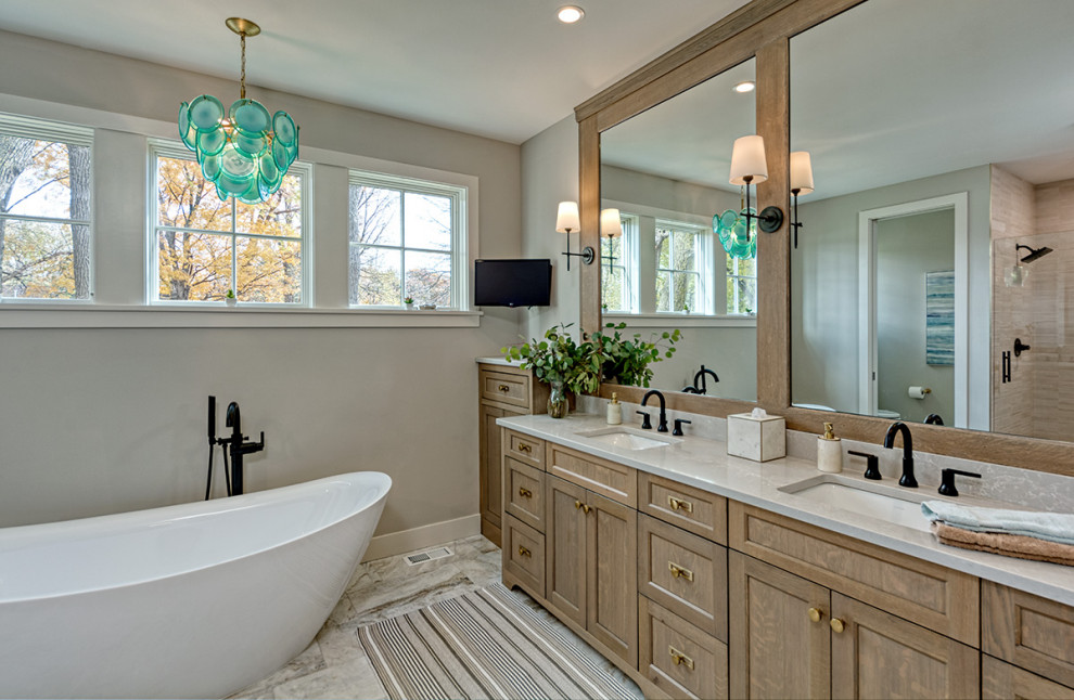 Photo of a small beach style master bathroom in Minneapolis with flat-panel cabinets, medium wood cabinets, a freestanding tub, a corner shower, a wall-mount toilet, grey walls, marble floors, an undermount sink, solid surface benchtops, beige floor, a hinged shower door and beige benchtops.