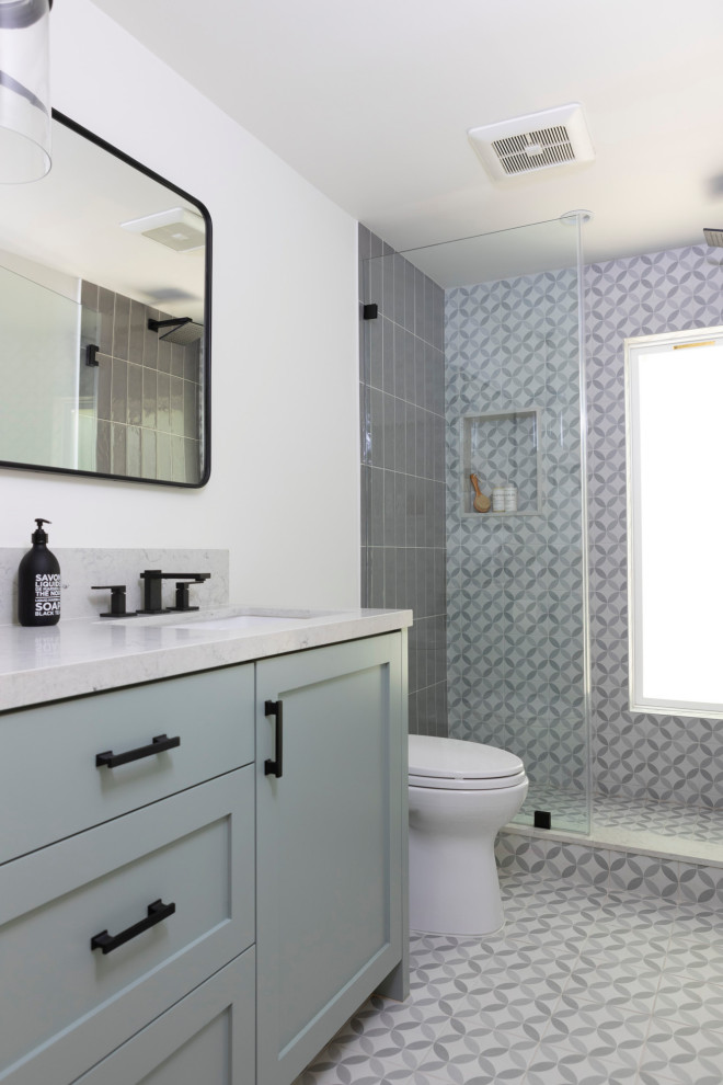 Photo of a mid-sized contemporary kids bathroom in Los Angeles with shaker cabinets, green cabinets, an alcove shower, a one-piece toilet, gray tile, ceramic tile, white walls, ceramic floors, an undermount sink, engineered quartz benchtops, grey floor, a hinged shower door, white benchtops, a single vanity and a built-in vanity.