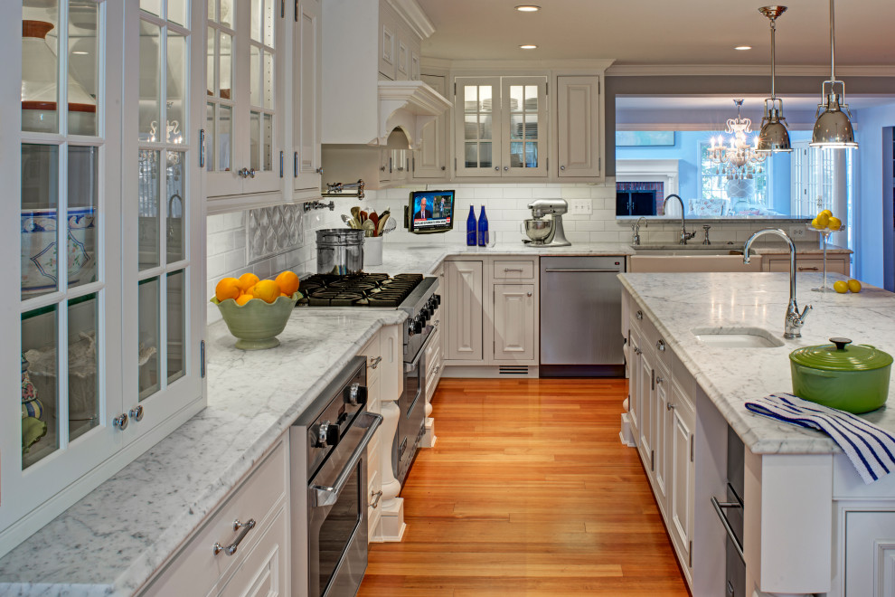 Example of a transitional medium tone wood floor and brown floor eat-in kitchen design in Baltimore with white cabinets, marble countertops, white backsplash, stainless steel appliances, an island and white countertops