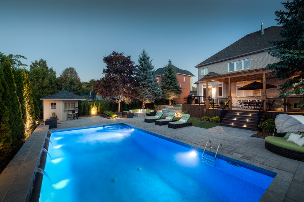 This is an example of a medium sized classic back swimming pool in Toronto with brick paving.