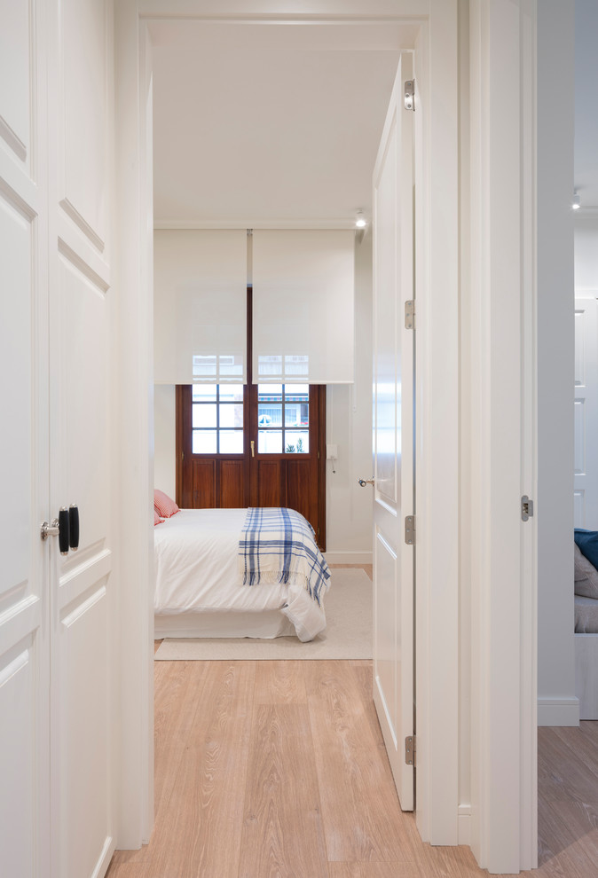 This is an example of a mid-sized contemporary gender-neutral walk-in wardrobe in Bilbao with raised-panel cabinets, white cabinets, laminate floors and brown floor.