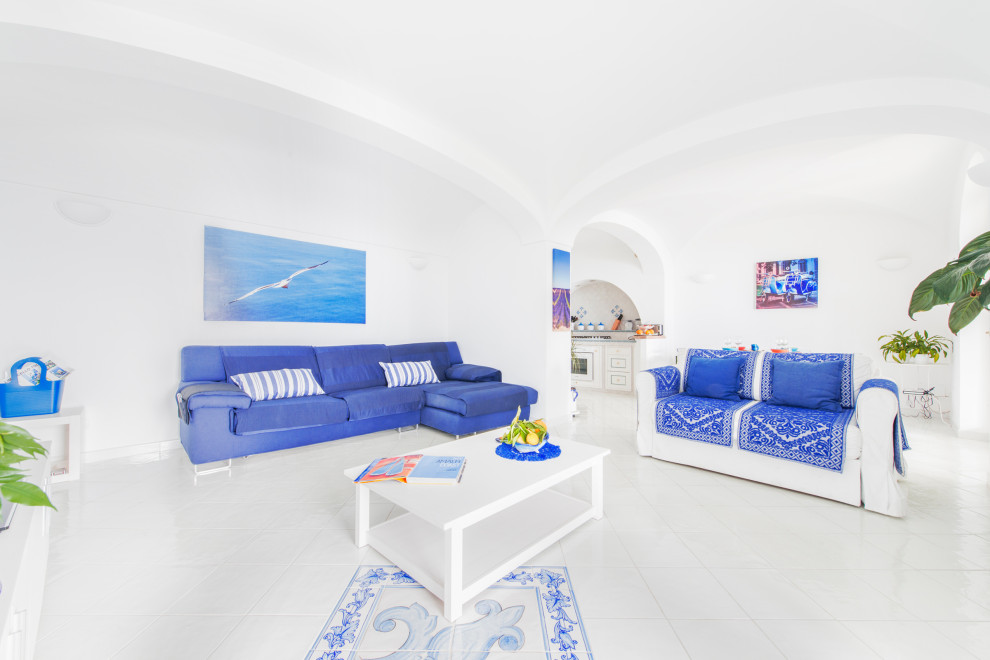 Ispirazione per un soggiorno mediterraneo di medie dimensioni e aperto con sala formale, pareti bianche, pavimento in gres porcellanato, parete attrezzata, pavimento bianco e soffitto a volta