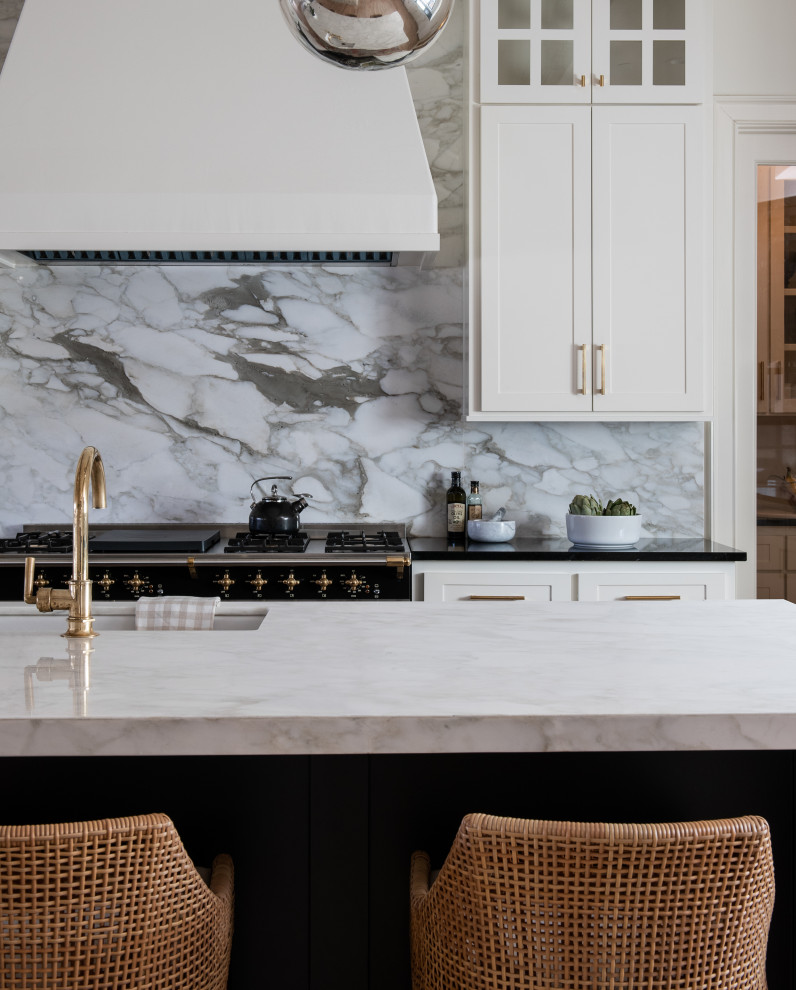 Expansive transitional galley open plan kitchen in Minneapolis with an undermount sink, recessed-panel cabinets, white cabinets, marble benchtops, white splashback, marble splashback, light hardwood floors, with island, white benchtop and exposed beam.