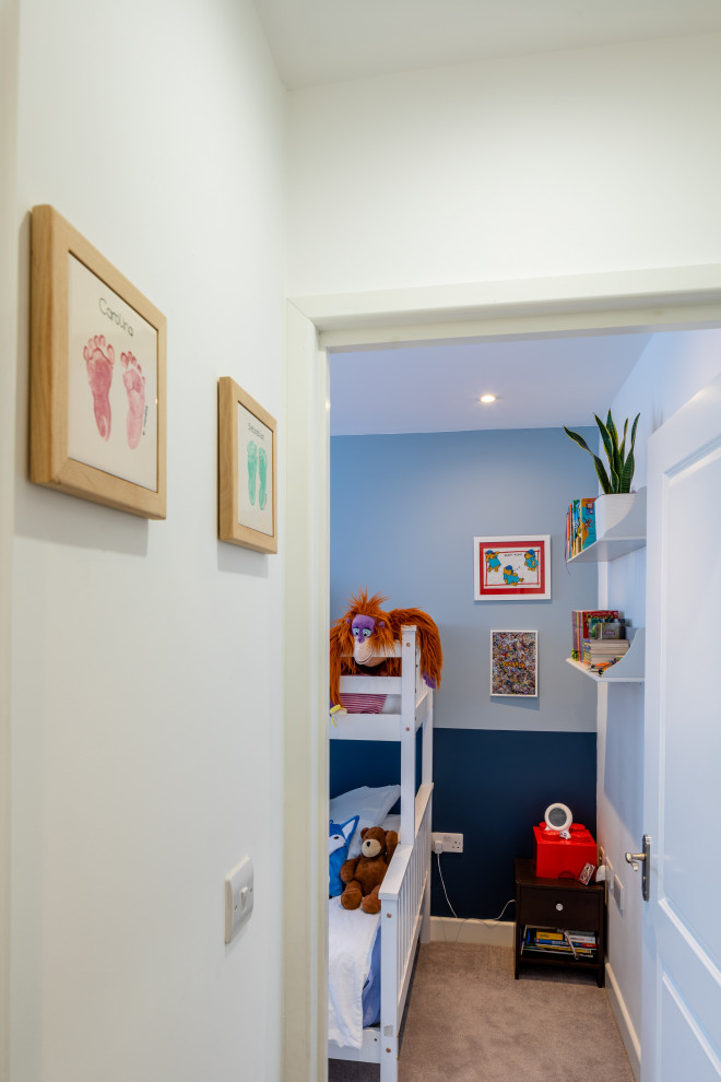 Photo of a small modern kids' bedroom for boys in London with blue walls, carpet and beige floor.