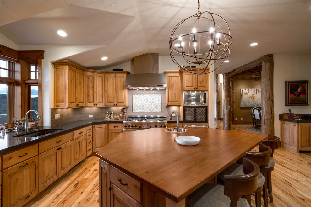 Inspiration for a country kitchen in Denver with a single-bowl sink, raised-panel cabinets, medium wood cabinets, brown splashback, stainless steel appliances, medium hardwood floors and with island.