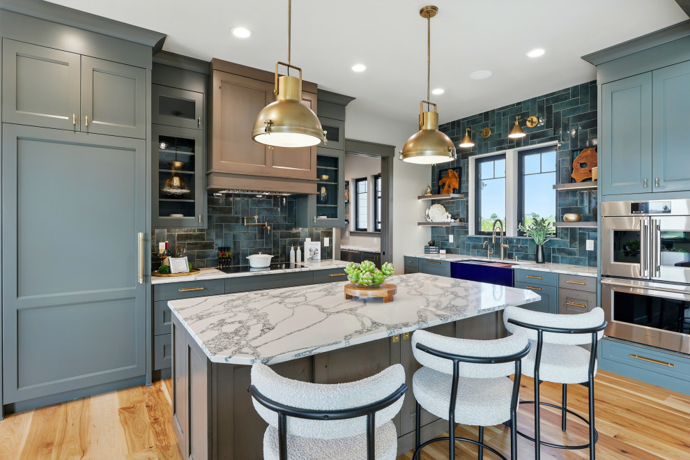 Inspiration for a transitional l-shaped medium tone wood floor and brown floor kitchen remodel in Denver with a farmhouse sink, shaker cabinets, blue cabinets, blue backsplash, stainless steel appliances, an island and white countertops
