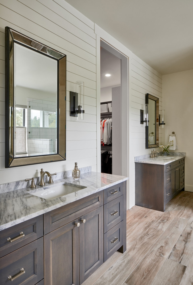Photo of a large country ensuite bathroom in Seattle with recessed-panel cabinets, brown cabinets, a freestanding bath, an alcove shower, a one-piece toilet, white tiles, ceramic tiles, white walls, a submerged sink, granite worktops, beige floors, a hinged door, black worktops, double sinks and a built in vanity unit.