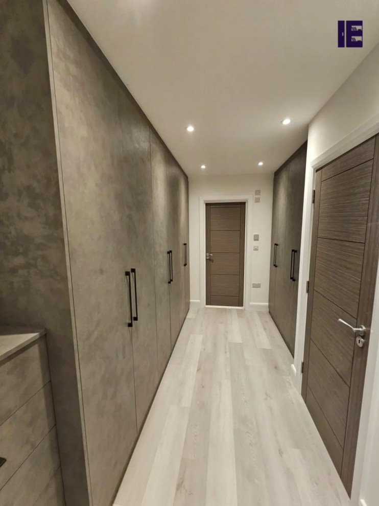 This is an example of a large modern built-in wardrobe in London with flat-panel cabinets and grey cabinets.