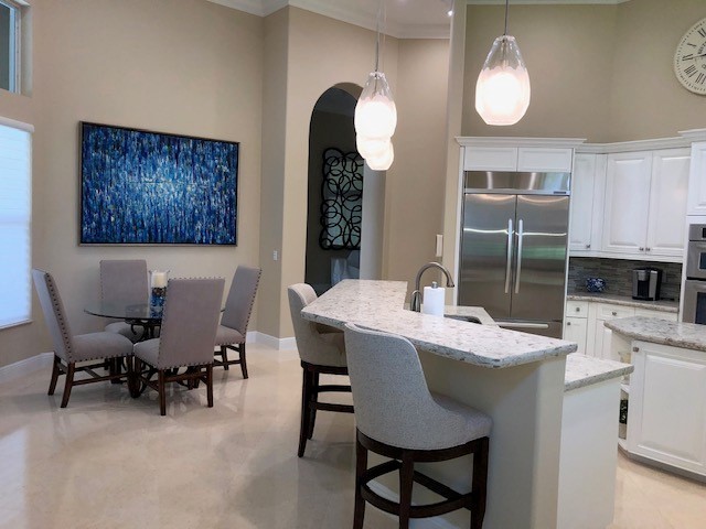 Transitional kitchen photo with a drop-in sink, quartz countertops, glass tile backsplash, stainless steel appliances and beige countertops