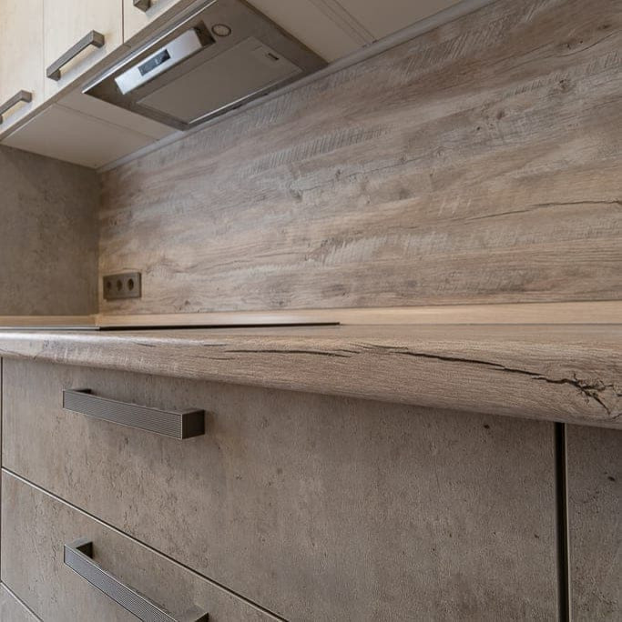 Угловая серо-белая кухня с современными ручками и фасадами под камень