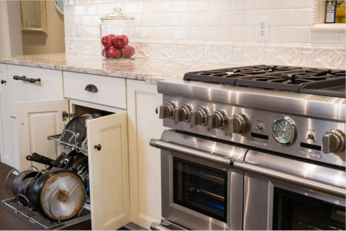 Kitchen cabinet door on concealed soft-close European hinge with pull-out cookware organizer beside the range