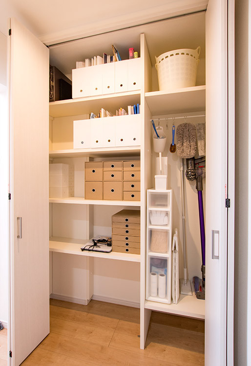 Mid-sized contemporary gender-neutral built-in wardrobe in Other with flat-panel cabinets, white cabinets, medium hardwood floors, brown floor and wallpaper.