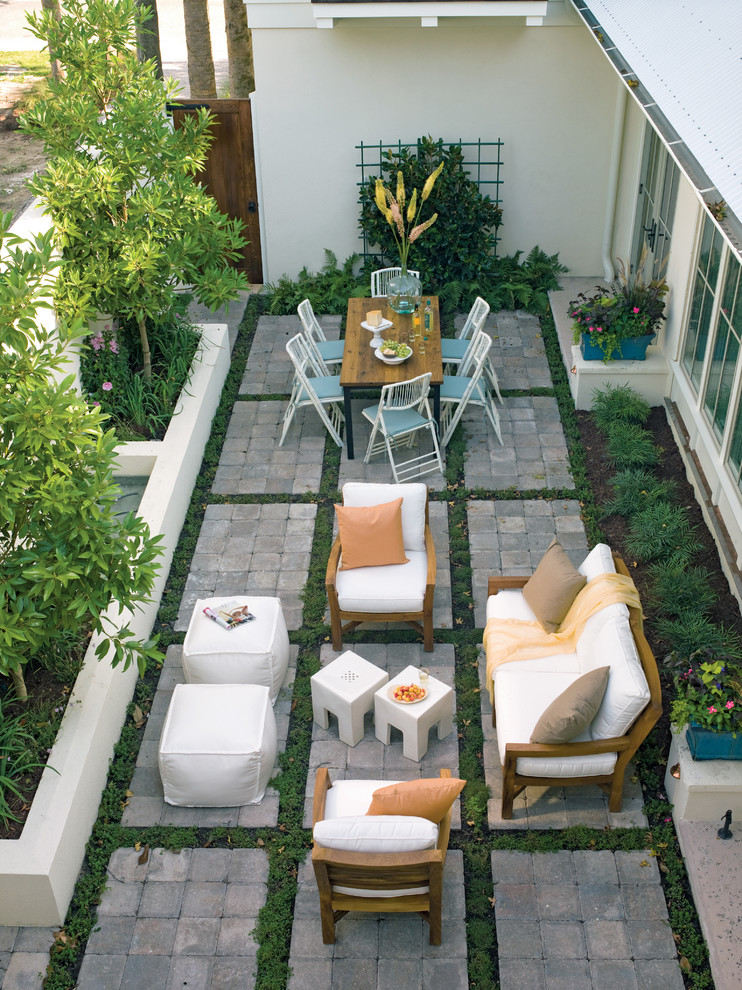 This is an example of a tropical patio in Charleston with concrete pavers and no cover.