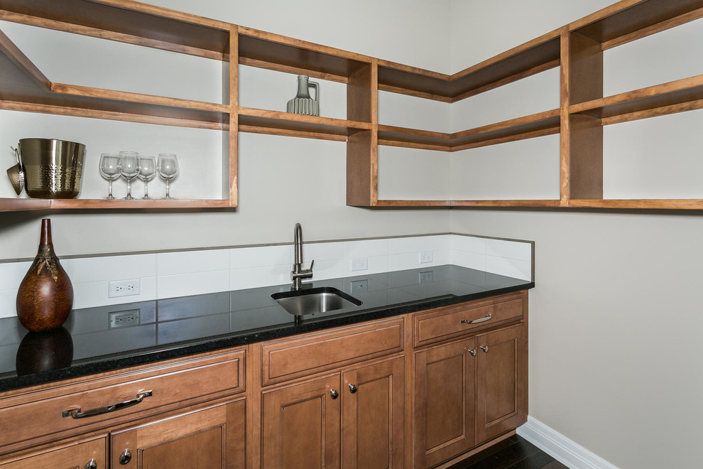 Transitional kitchen pantry in Wichita with an undermount sink, dark wood cabinets, quartzite benchtops, white splashback, porcelain splashback, recessed-panel cabinets and black benchtop.