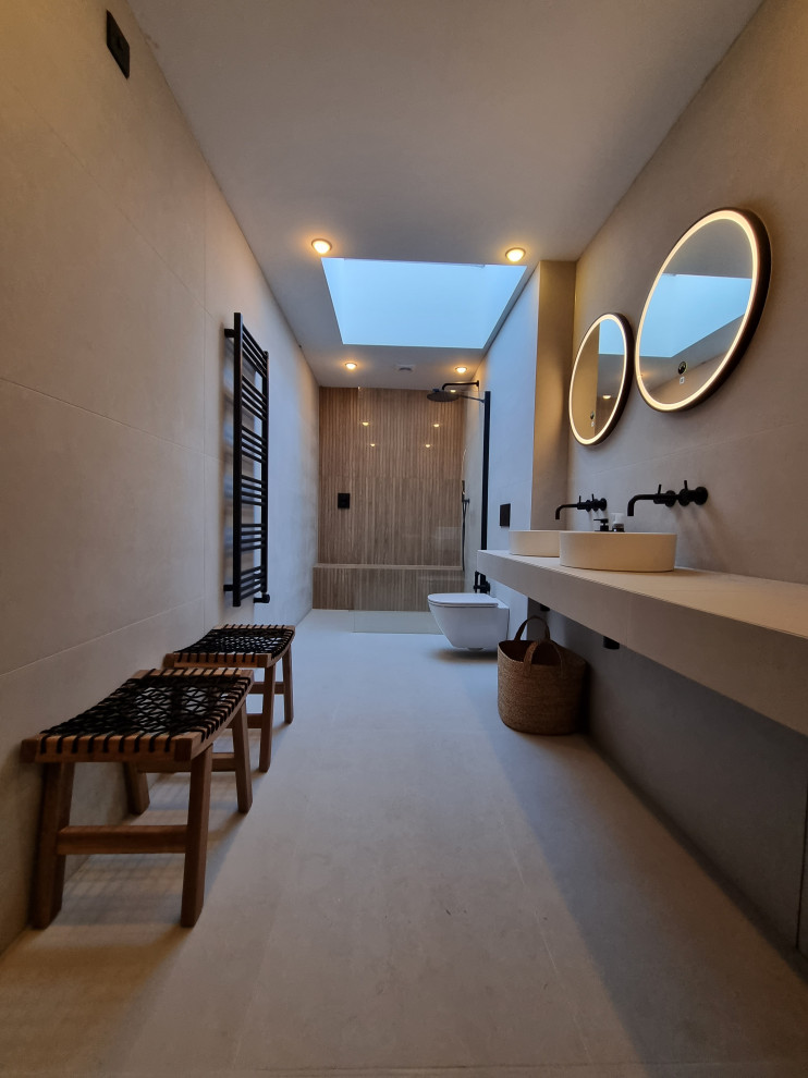 Foto på ett stort nordiskt vit en-suite badrum, med vita skåp, ett japanskt badkar, en öppen dusch, en vägghängd toalettstol, vit kakel, porslinskakel, vita väggar, klinkergolv i porslin, ett fristående handfat, kaklad bänkskiva och vitt golv