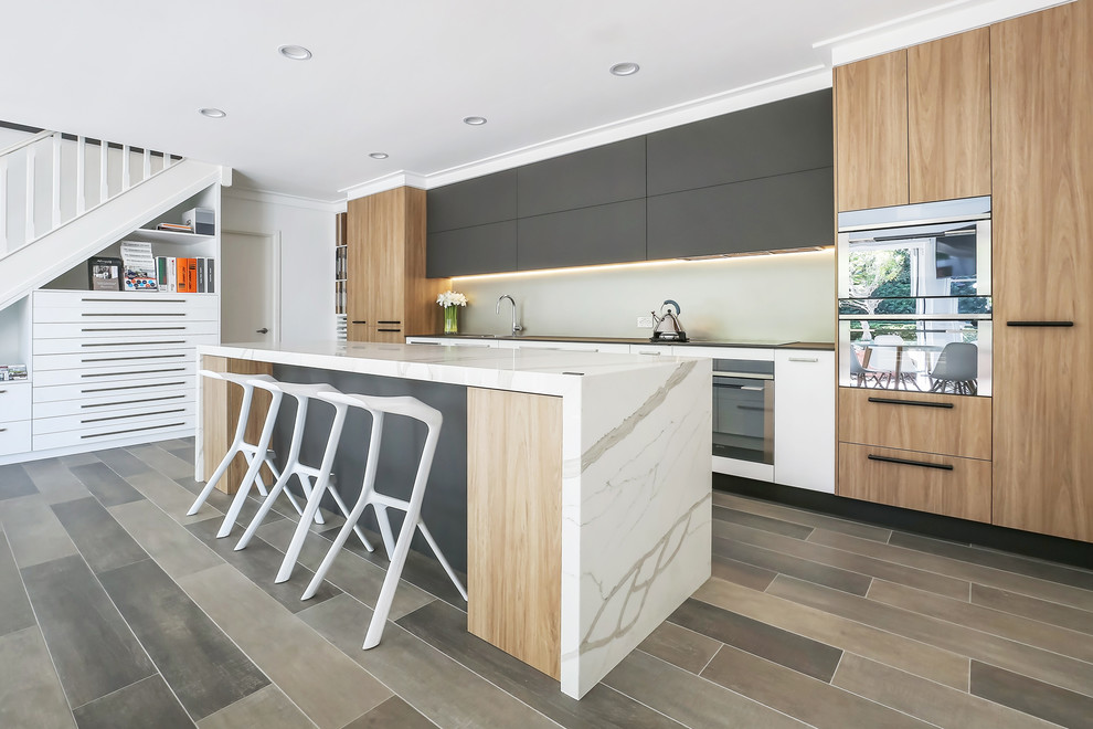 Inspiration for a large contemporary single-wall open plan kitchen in Sydney with a drop-in sink, flat-panel cabinets, brown cabinets, quartz benchtops, metallic splashback, porcelain splashback, stainless steel appliances, porcelain floors, with island, brown floor and white benchtop.