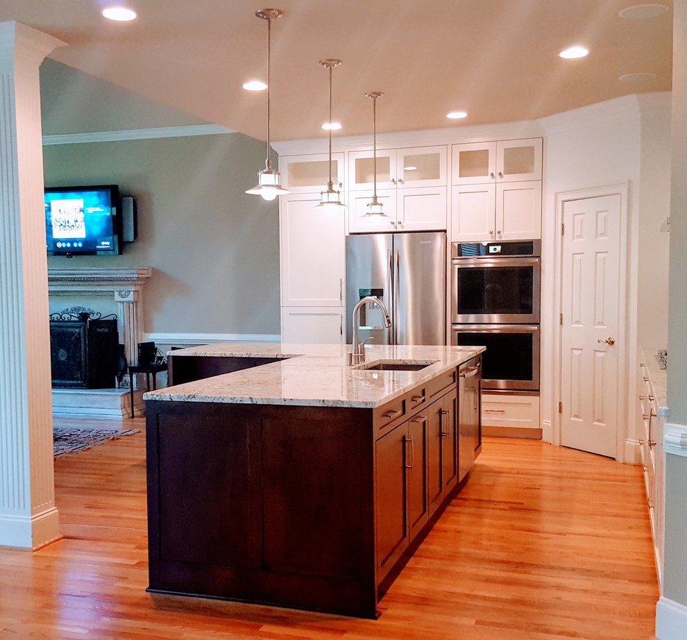 Transitional l-shaped eat-in kitchen in Atlanta with an undermount sink, shaker cabinets, white cabinets, granite benchtops, glass tile splashback, stainless steel appliances, medium hardwood floors and with island.