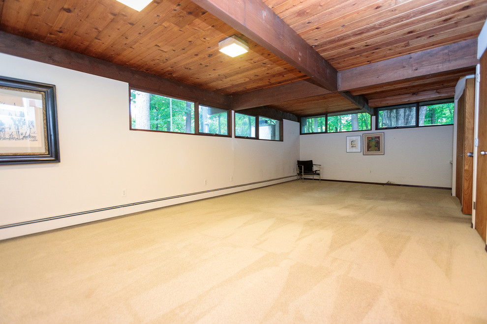 Large midcentury enclosed family room in Boston with white walls, carpet and beige floor.