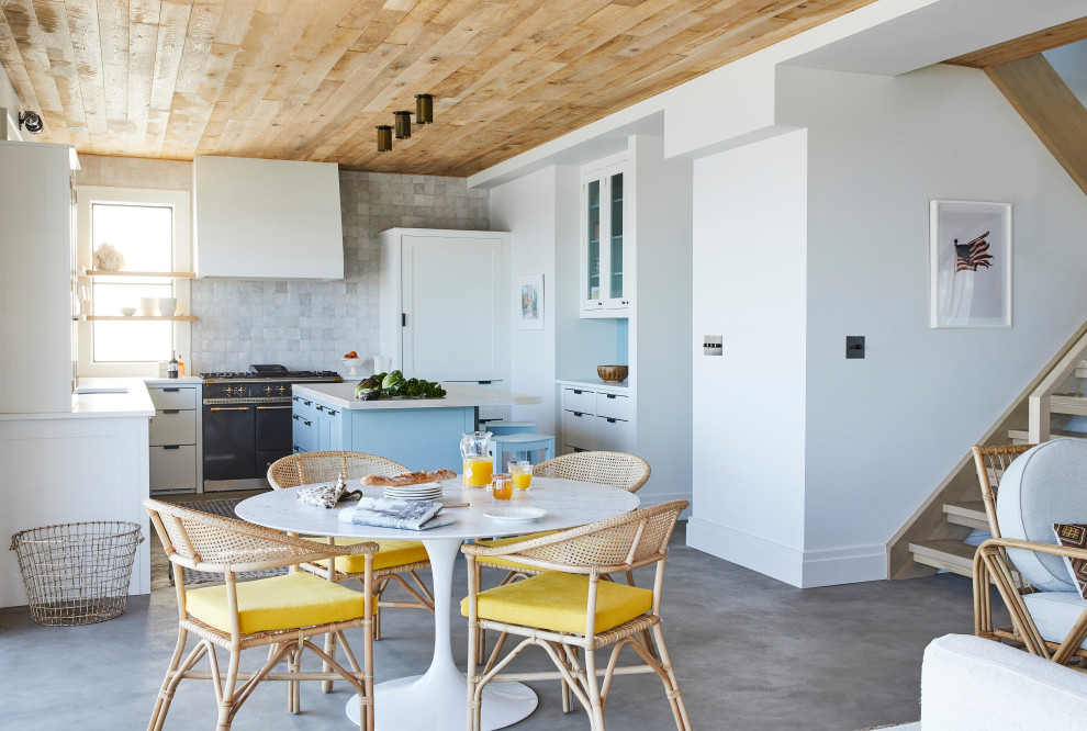 This is an example of a beach style u-shaped kitchen in New York with shaker cabinets, white splashback, terra-cotta splashback, concrete floors, with island, grey floor, white benchtop and wood.
