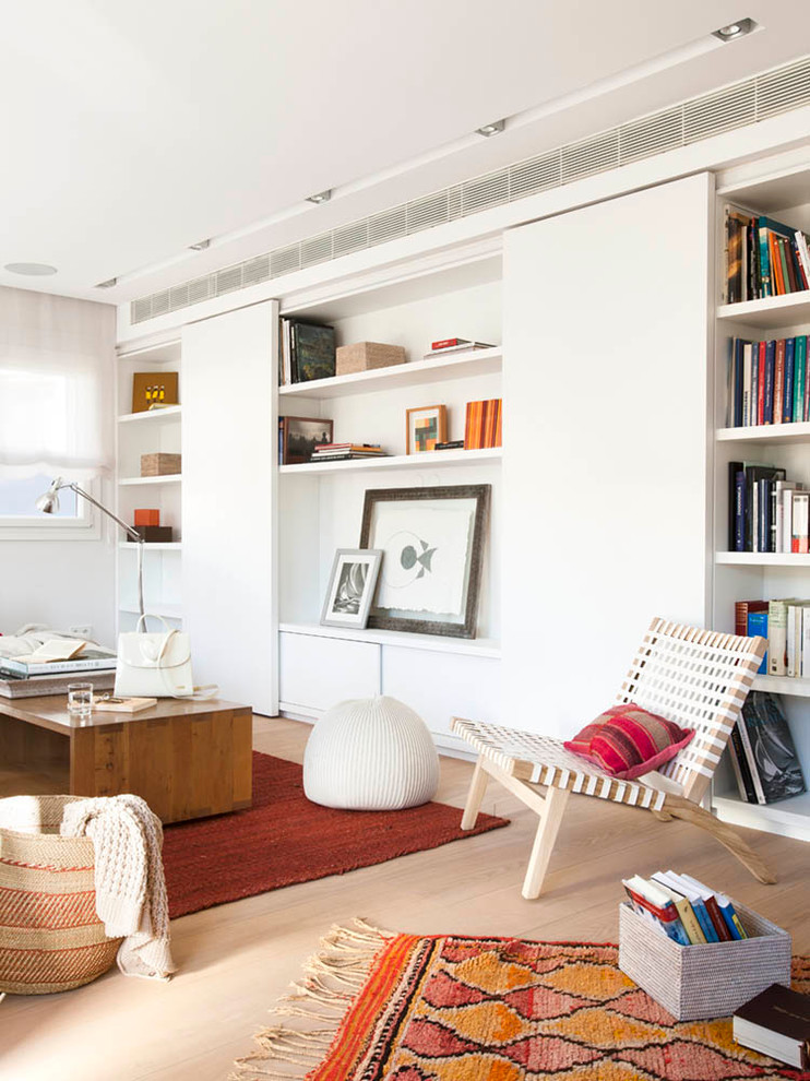 Mid-sized scandinavian open concept family room in Palma de Mallorca with a library, white walls, medium hardwood floors, no fireplace and no tv.