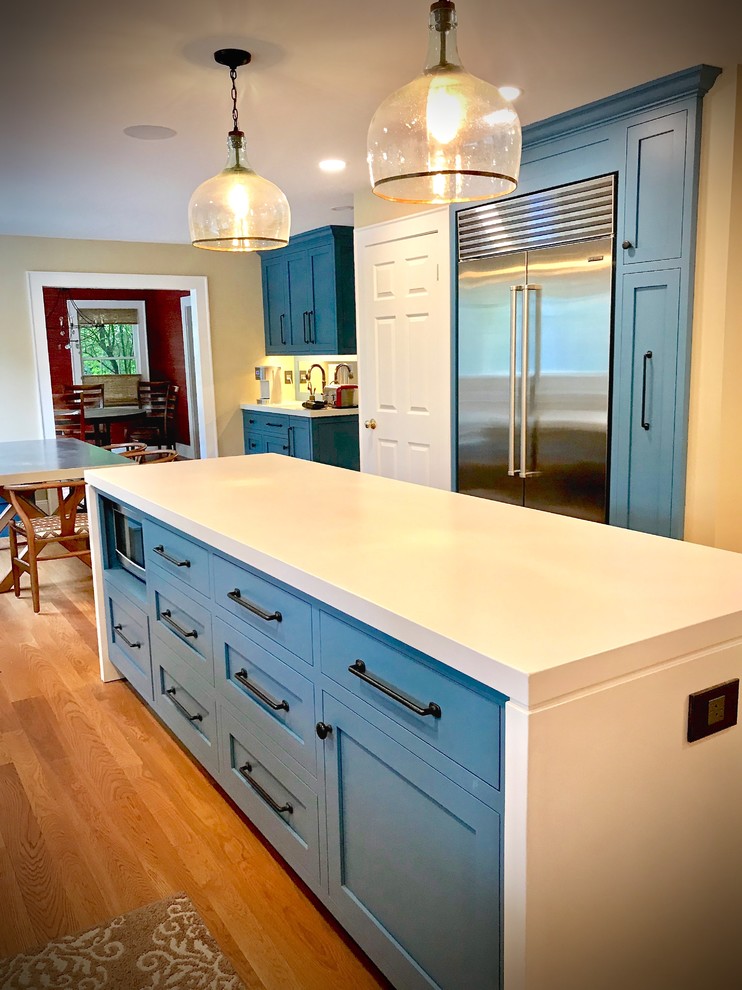 Eat-in kitchen - large rustic l-shaped medium tone wood floor and brown floor eat-in kitchen idea with a farmhouse sink, flat-panel cabinets, blue cabinets, concrete countertops, red backsplash, brick backsplash, stainless steel appliances, an island and white countertops