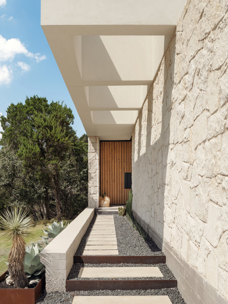 Aménagement d'une porte d'entrée moderne avec un mur beige, un sol en calcaire, une porte pivot et une porte en bois brun.
