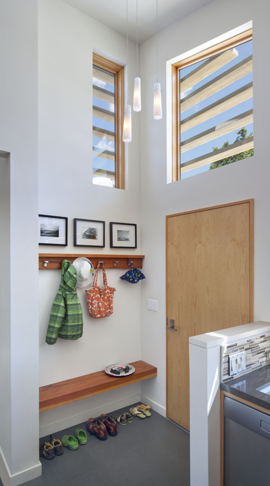 This is an example of a contemporary foyer in San Francisco with white walls, porcelain floors, a single front door and a light wood front door.