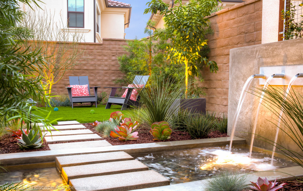 This is an example of a small modern backyard partial sun formal garden in Orange County with concrete pavers.
