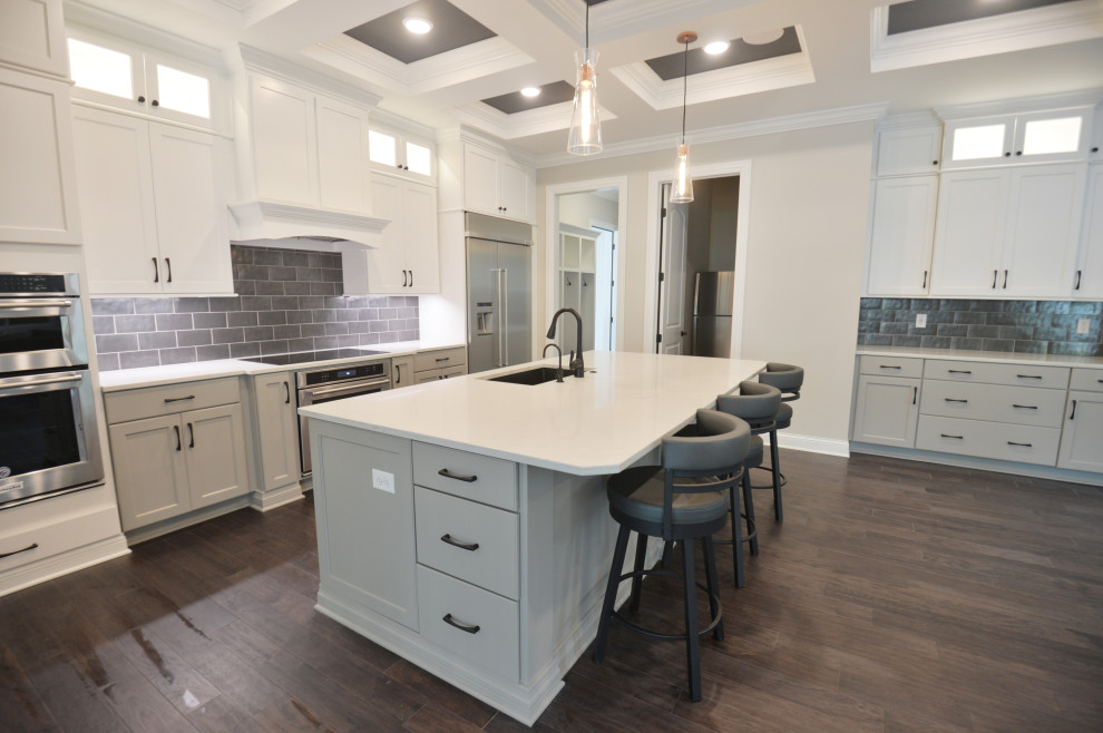 Example of a transitional medium tone wood floor and coffered ceiling eat-in kitchen design in Columbus with a single-bowl sink, shaker cabinets, gray cabinets, quartz countertops, gray backsplash, ceramic backsplash, stainless steel appliances, an island and white countertops