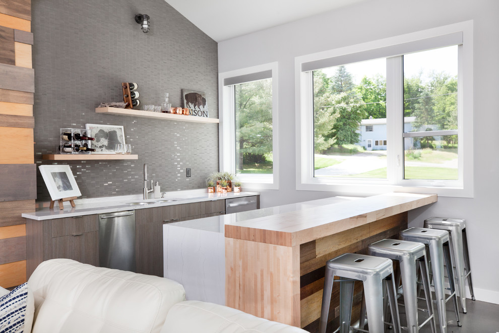 This is an example of a contemporary galley seated home bar in Other with an undermount sink, flat-panel cabinets, mosaic tile splashback, grey floor, white benchtop and medium wood cabinets.
