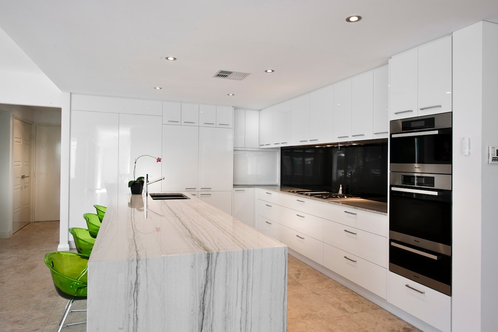 Photo of a mid-sized modern u-shaped open plan kitchen in Perth with a double-bowl sink, flat-panel cabinets, white cabinets, granite benchtops, black splashback, glass sheet splashback, stainless steel appliances, marble floors and with island.
