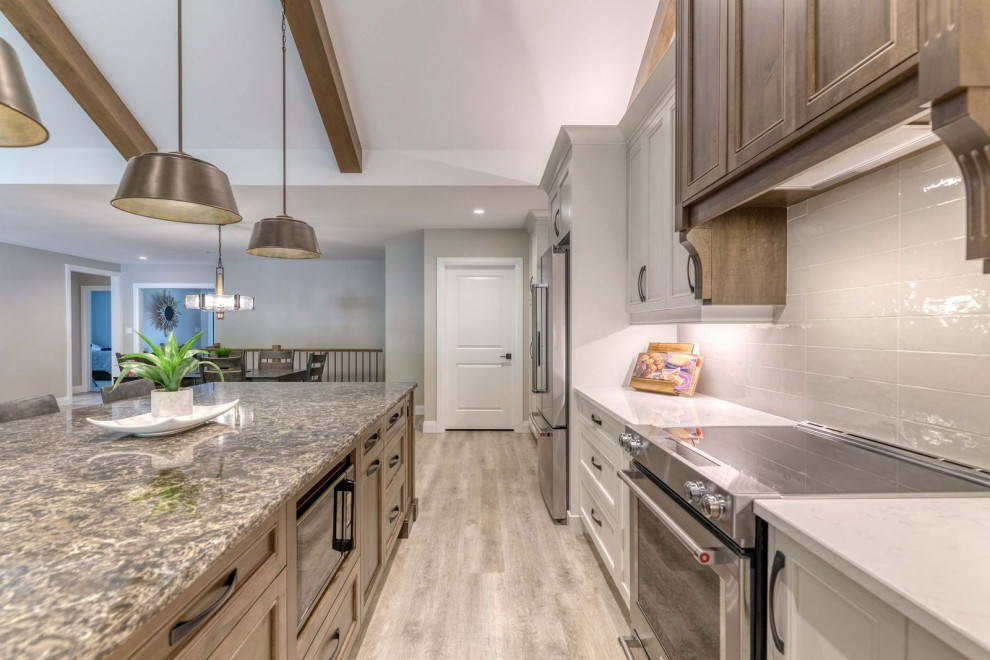 Large transitional eat-in kitchen photo with an undermount sink, shaker cabinets, quartz countertops, porcelain backsplash, stainless steel appliances and an island