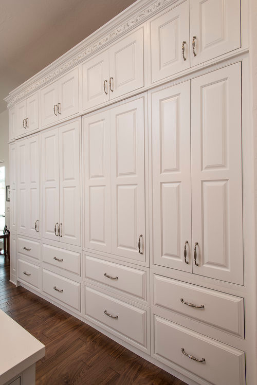 Example of a mid-sized classic u-shaped medium tone wood floor and brown floor eat-in kitchen design in Phoenix with a farmhouse sink, raised-panel cabinets, white cabinets, quartz countertops, beige backsplash, paneled appliances and two islands