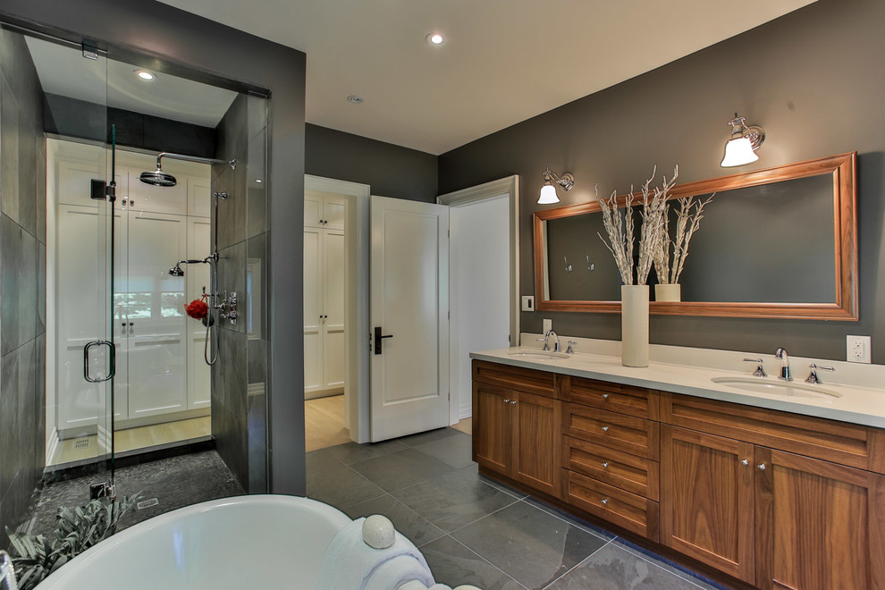 Large transitional master gray tile and stone tile slate floor freestanding bathtub photo in Toronto with shaker cabinets, medium tone wood cabinets, quartz countertops, a two-piece toilet, gray walls and an undermount sink
