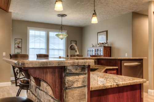 Inspiration for a brown floor open concept kitchen remodel in Portland with an undermount sink, red cabinets, granite countertops, stainless steel appliances, an island and beige countertops