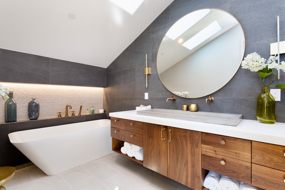 Inspiration for a contemporary master bathroom in Los Angeles with flat-panel cabinets, medium wood cabinets, a freestanding tub, gray tile, concrete floors, a drop-in sink, engineered quartz benchtops, beige floor, white benchtops, a double vanity, a floating vanity and vaulted.