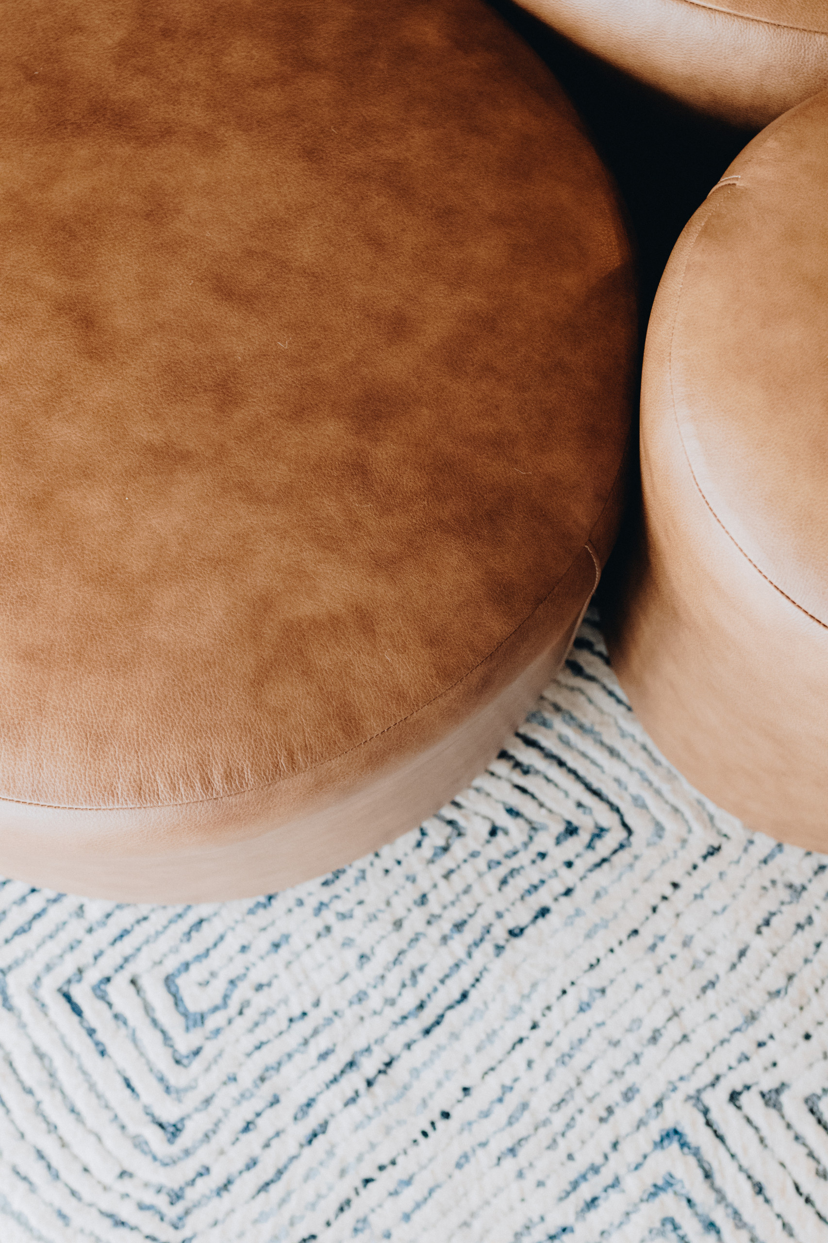 Three leather ottomans on a blue and white rug