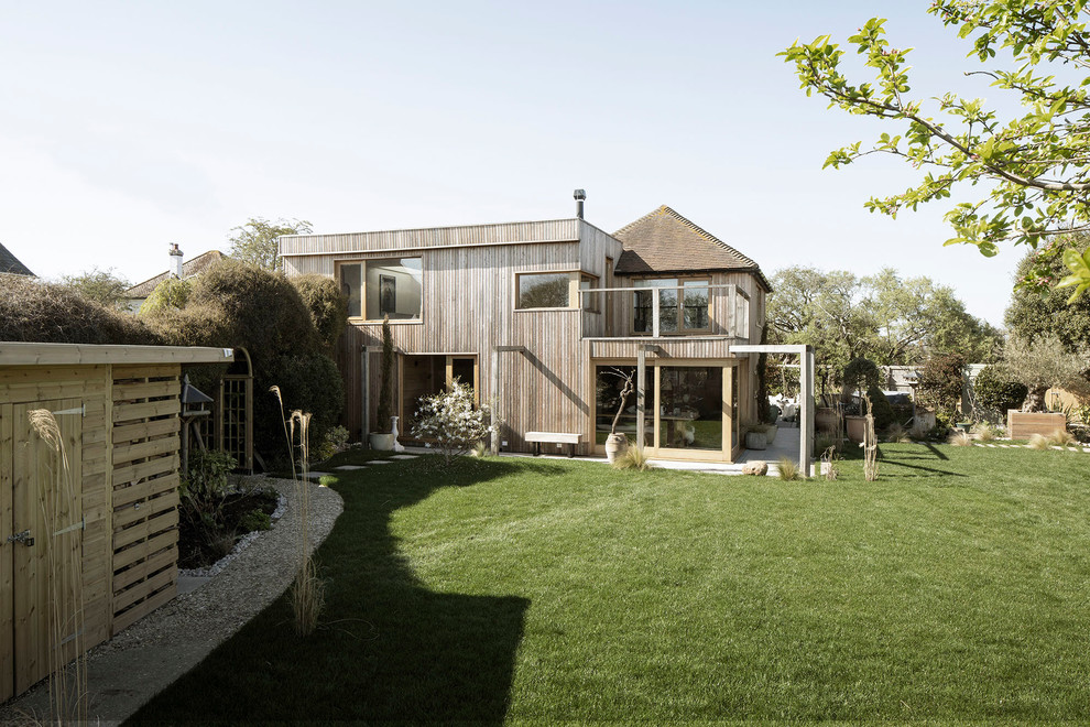 Photo of a large beach style two-storey brown house exterior in Sussex with wood siding, a flat roof and a green roof.