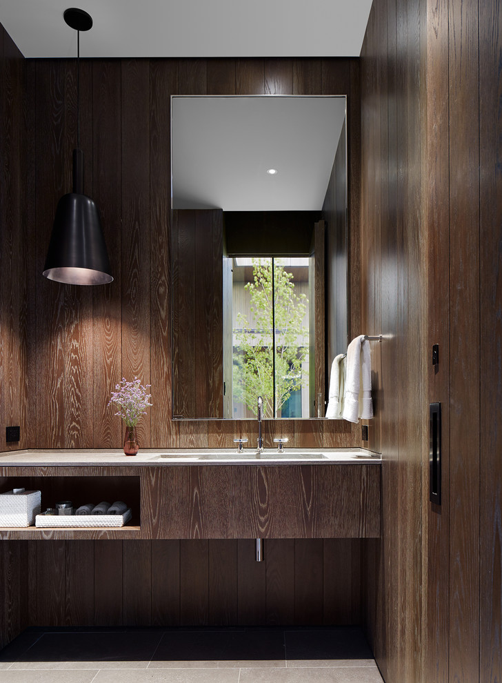 Inspiration for a modern powder room in Denver with flat-panel cabinets, medium wood cabinets, white tile, limestone floors, an integrated sink, limestone benchtops, grey floor and brown walls.