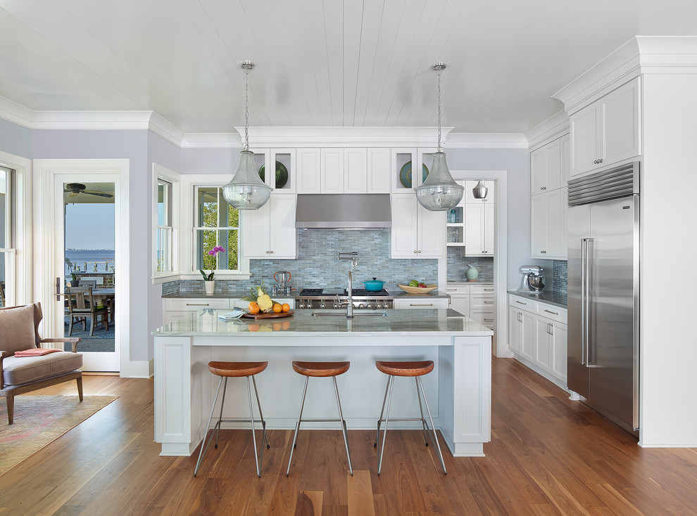 Inspiration for a beach style kitchen in Charleston with an undermount sink, shaker cabinets, white cabinets, multi-coloured splashback, mosaic tile splashback, stainless steel appliances, medium hardwood floors, with island and granite benchtops.