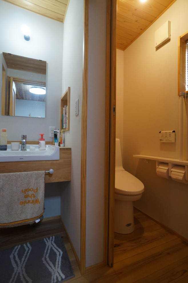 Idées déco pour un WC et toilettes asiatique de taille moyenne avec WC à poser, un mur blanc, un sol en bois brun, un lavabo encastré, un plan de toilette en bois, un sol marron, meuble-lavabo encastré et un plafond en bois.