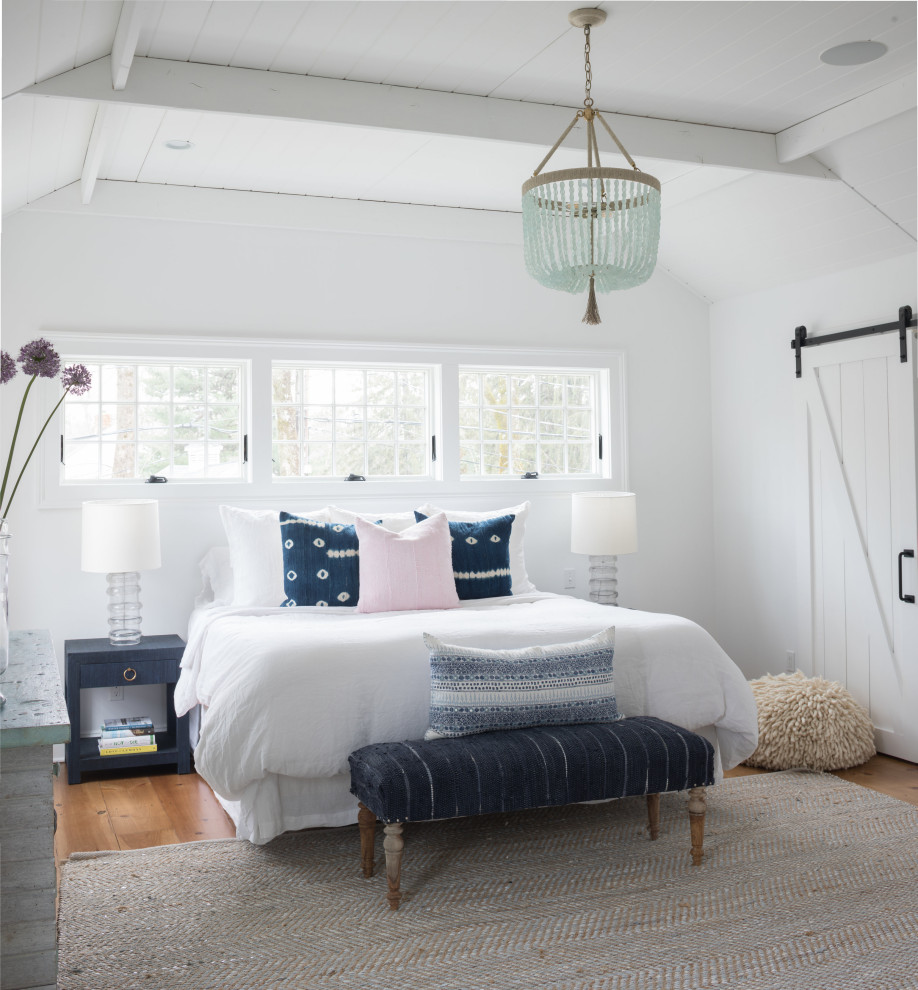 Imagen de dormitorio principal costero grande con paredes blancas, suelo de madera clara, suelo marrón y machihembrado