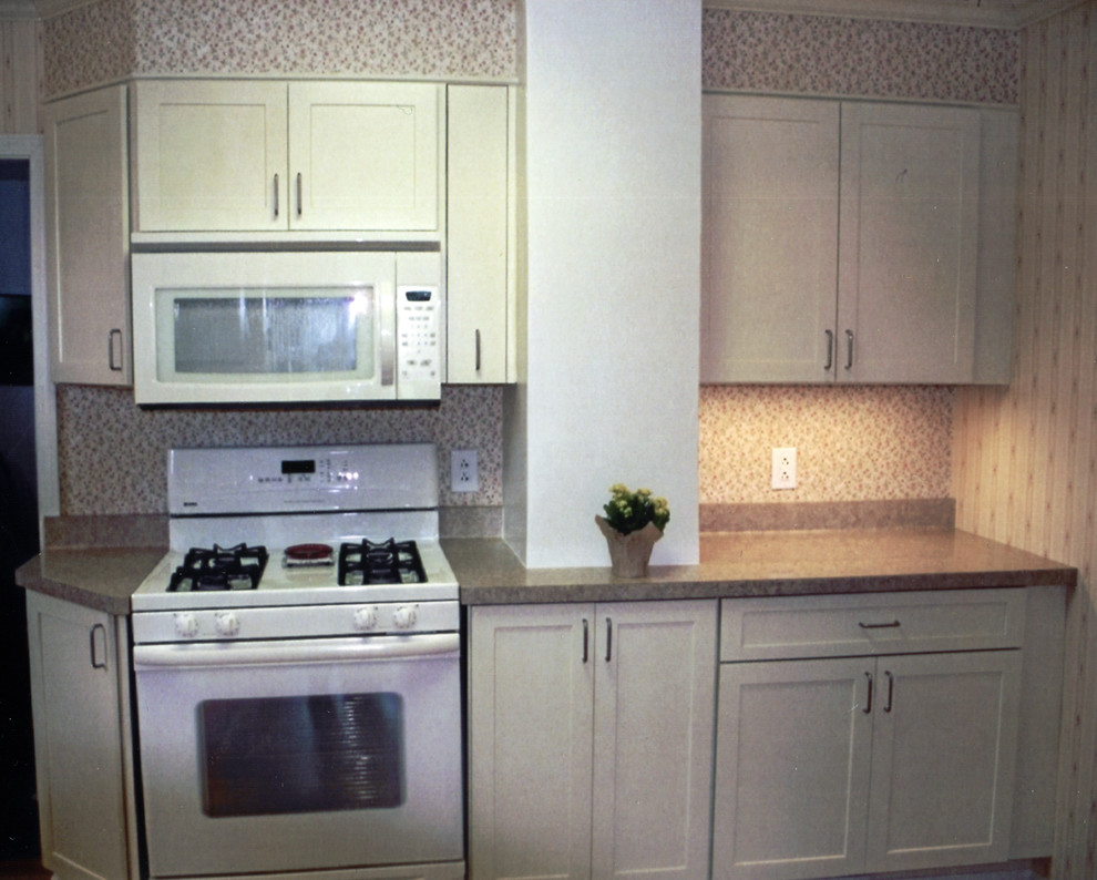 Mid-sized transitional l-shaped medium tone wood floor and brown floor kitchen pantry photo with a double-bowl sink, recessed-panel cabinets, white cabinets, laminate countertops, white appliances, no island and brown countertops