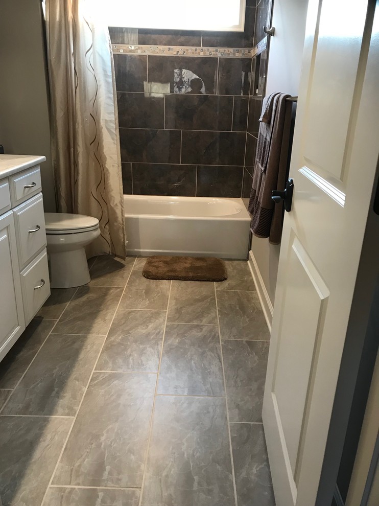 This is an example of a mid-sized mediterranean kids bathroom in Baltimore with raised-panel cabinets, white cabinets, an alcove tub, a two-piece toilet, brown tile, ceramic tile, grey walls, ceramic floors, a drop-in sink, granite benchtops, beige floor and a shower curtain.
