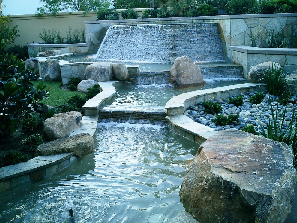 Large modern front yard full sun garden in San Diego with a water feature and natural stone pavers for summer.