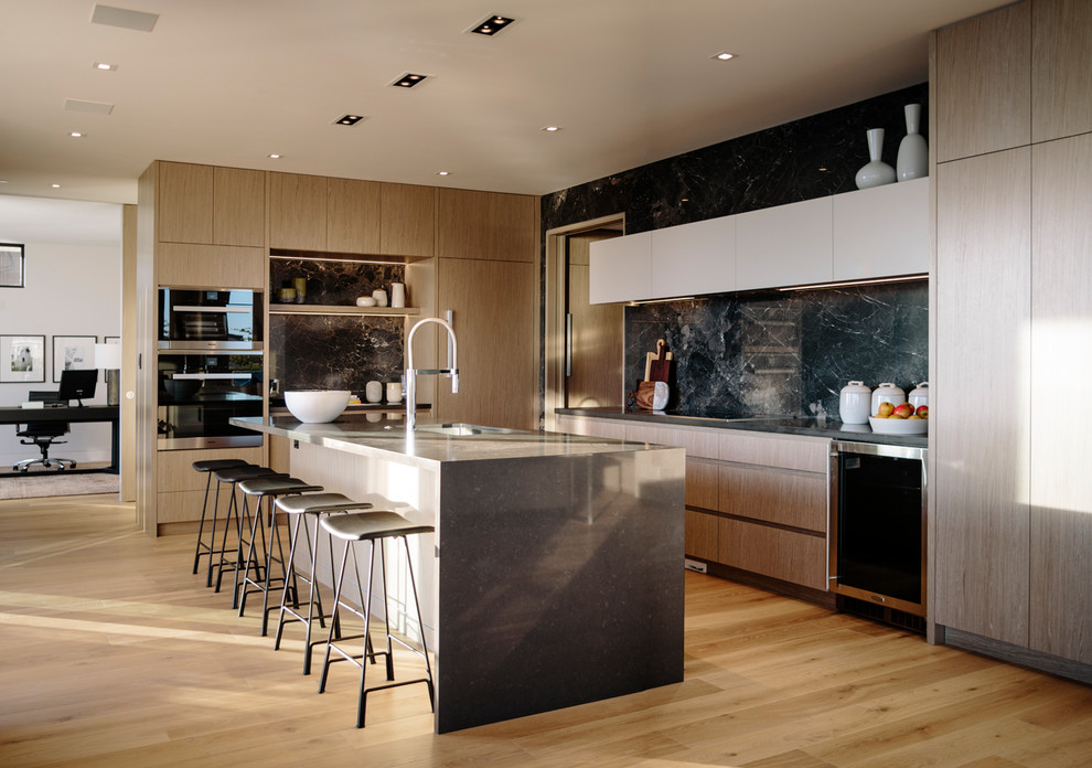 Large contemporary galley eat-in kitchen in Vancouver with an undermount sink, flat-panel cabinets, medium wood cabinets, quartz benchtops, grey splashback, porcelain splashback, stainless steel appliances, medium hardwood floors, with island and grey benchtop.