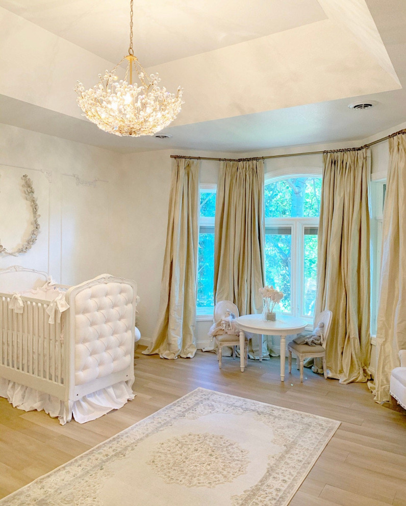 Réalisation d'une chambre de bébé fille avec un mur blanc, parquet clair et un plafond décaissé.