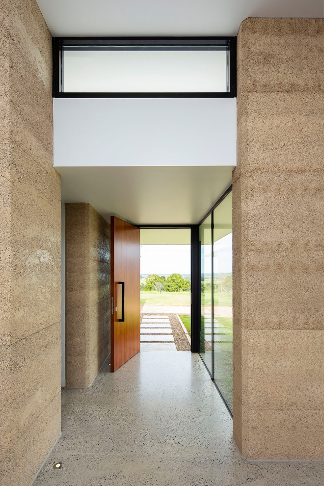 Mid-sized contemporary front door in Other with beige walls, concrete floors, a pivot front door, a medium wood front door and grey floor.