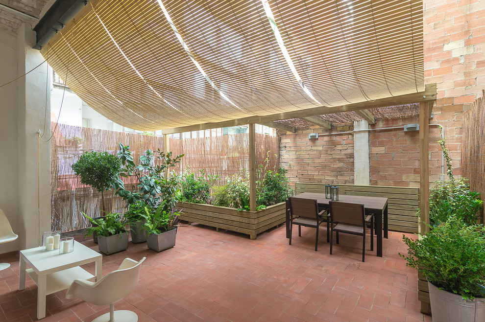 Mediterranean backyard verandah in Barcelona with a container garden, brick pavers and a roof extension.